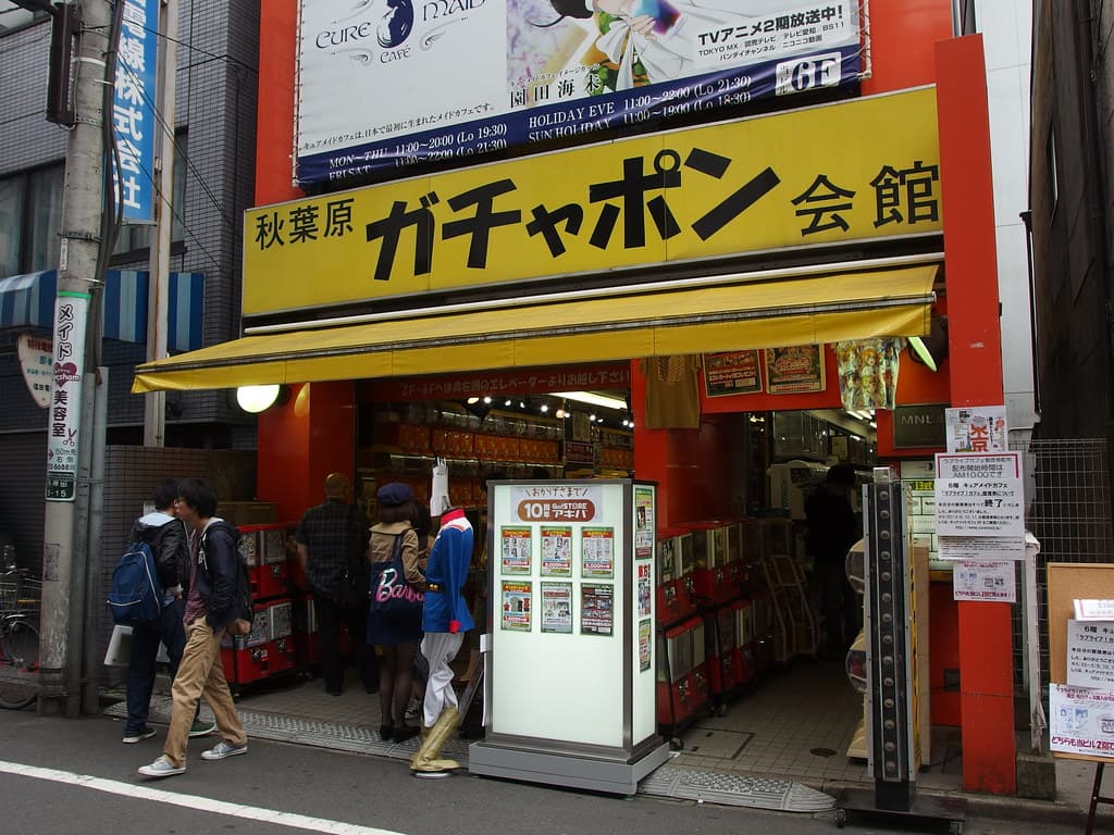 The storefront of Akihabara Gachapon Kaikan, its yellow signage above rows of capsule-toy vending machines