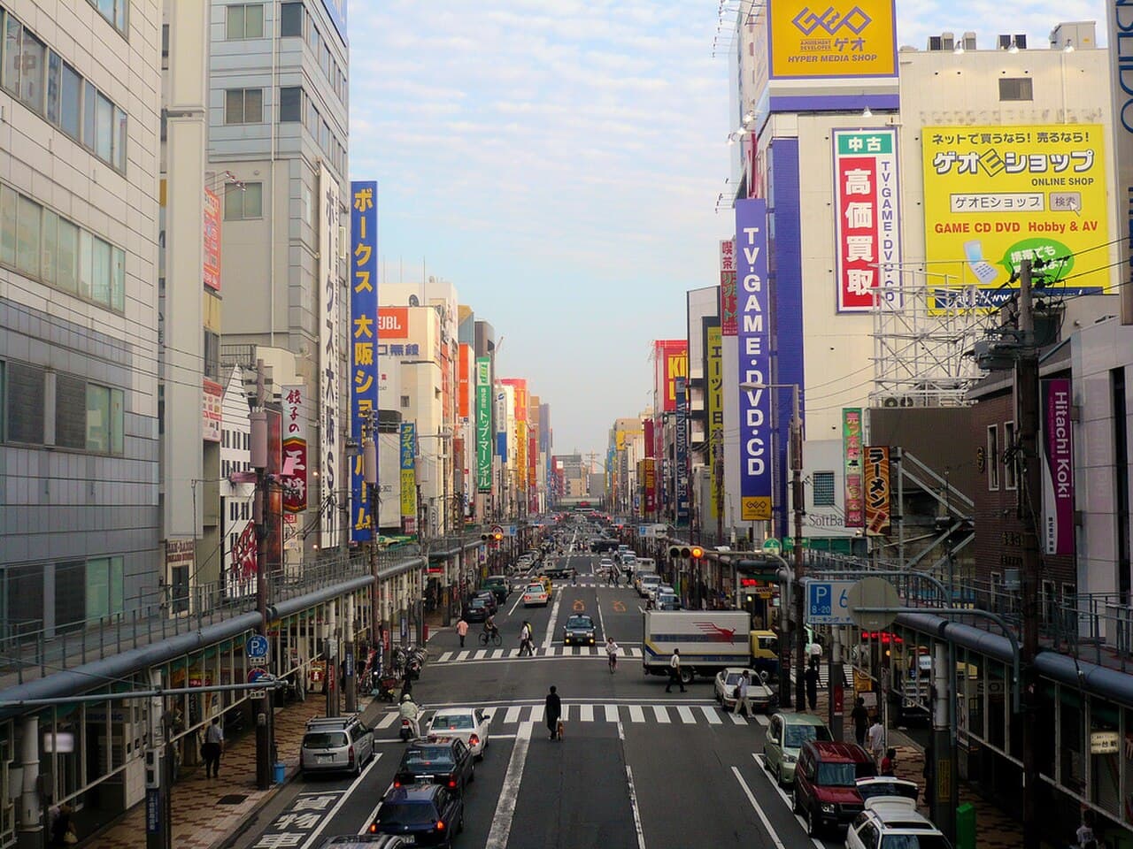 An elevated view of Den Den Town's main electronics and hobby-shop street in Osaka's Nipponbashi district, home to Mandarake Grand Chaos