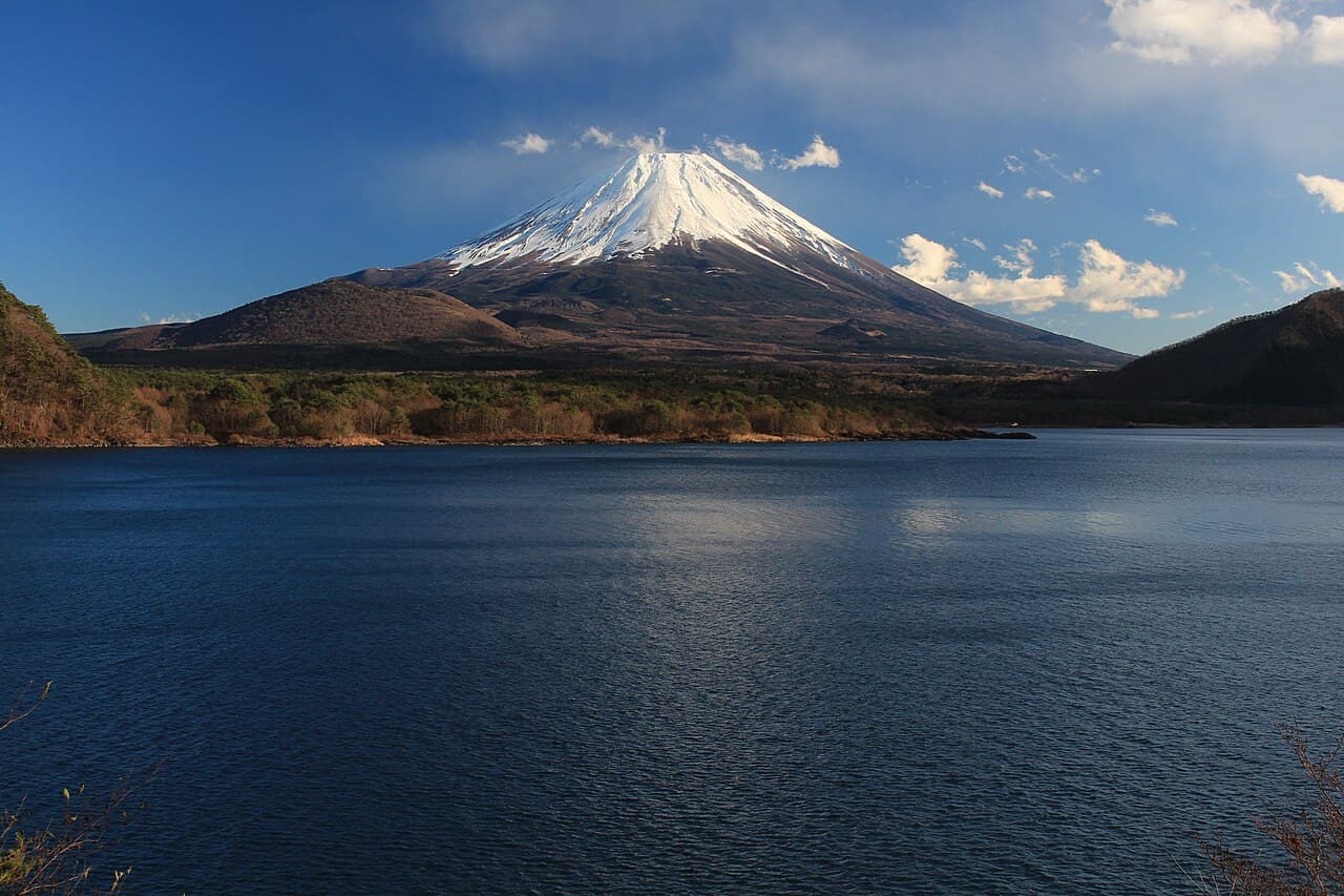 雪をかぶった富士山と、手前に広がる濃い青の本栖湖。対岸には木々の茂った低い丘が続く