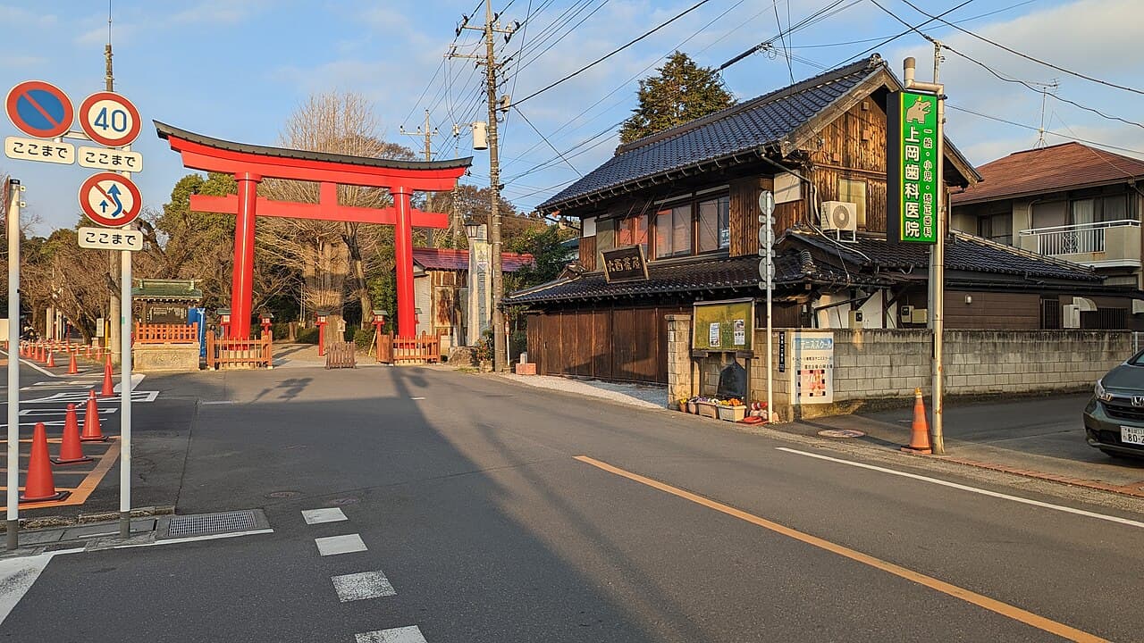 The large red torii gate at the entrance of Washinomiya Shrine in Kuki, Saitama, seen from across the street — the real-world setting famous from the Lucky Star anime opening.
